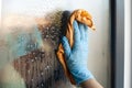 Closeup shot of a hand in glove cleaning window with yellow cloth Royalty Free Stock Photo