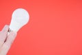 Closeup shot of a hand holding a LED light bulb on a red background Royalty Free Stock Photo