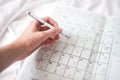 Closeup shot of a hand making notes in a small calendar on the bed Royalty Free Stock Photo