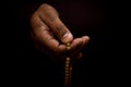 Closeup shot of a hand of a Muslim man praying in a dark background