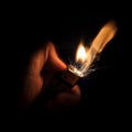 Closeup shot of a hand of a person lighting a lighter in the darkness Royalty Free Stock Photo