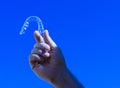 Closeup shot of a hand with transparent orthodontic appliance on blue background