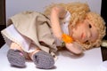 Closeup shot of a handmade fabric doll with blond hair and knitted clothing lying on a white paper