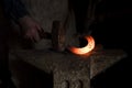 Closeup shot of the hands of a blacksmith hammering a hot horseshoe