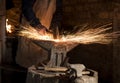 Closeup shot of the hands of a blacksmith hammering a hot horseshoe