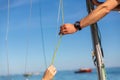 Closeup shot of hands holding a boat rope with blue sky in background Royalty Free Stock Photo