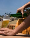 Closeup shot of hands pouring cold beer into a glass at a beach Royalty Free Stock Photo