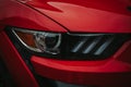 Closeup shot of a headlight on a sleek, modern red sportscar