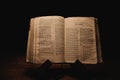 Closeup shot of a historic old Bible open on the Jeremiah pages on display in a dark room