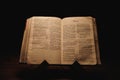 Closeup shot of a historic old Bible open on the Micah pages on display in a dark room