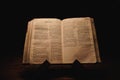 Closeup shot of a historic old Bible open on the Obadiah pages on display in a dark room Royalty Free Stock Photo