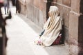 Closeup shot of a homeless elderly sitting on the ground with a blurred background