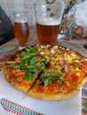 Closeup shot of a homemade pizza with two flavors and jars of beer on a table Royalty Free Stock Photo