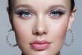 Closeup shot of human female face with unusual rhinestones makeup. Woman with earring in the form of a shiny ring in the ear