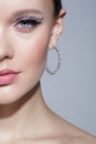 Closeup shot of human female face with unusual rhinestones makeup. Woman with earring in the form of a shiny ring in the ear Royalty Free Stock Photo