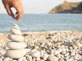 Closeup shot of a human hand putting the beautiful white stones of the seashore on each other Royalty Free Stock Photo