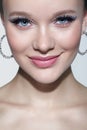 Closeup shot of human smiling female face with unusual rhinestones makeup. Woman with earring in the form of a shiny ring in the