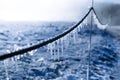 Closeup shot of icicles hanging on a frozen wire on the background of the frozen earth Royalty Free Stock Photo