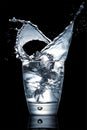 Closeup shot of an impressive water splash in a glass cup on a black background Royalty Free Stock Photo