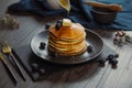 Closeup shot of a jug pouring maple syrup on a pile of pancakes with butter and blueberries Royalty Free Stock Photo