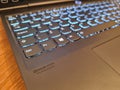 Closeup shot of a keyboard with the blue lights of a black laptop on a table