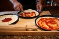 Closeup shot of a kitchen table with a person& x27;s hand preparing Italian pizza at home Royalty Free Stock Photo