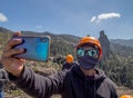 Closeup shot of a Latin male rock climber on a mountain taking a selfie in a facemask Royalty Free Stock Photo