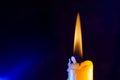 Closeup shot of a light candle with wax dripping against a dark blue background Royalty Free Stock Photo