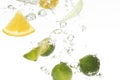 Closeup shot of lime and lemon slices dropping into water Royalty Free Stock Photo