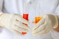 Closeup shot of liquid in glass in test tube holded by scientist in white lab coat and rubber gloves hands