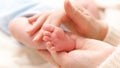 Closeup shot of little newborn baby feet in gentle mothers hands. Concept of family happiness and loving parents with Royalty Free Stock Photo