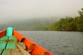 Closeup shot of a little orange rowboat floating in the early morning mist in the rainforest Royalty Free Stock Photo