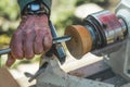 Closeup shot of male carpenter artist creating wooden art pieces with the use of lathe. Outdoor shot. Dutch town.