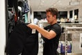 Closeup shot of a male customer holding two pairs of black pants in a clothing store