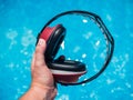 Closeup shot of male hand holding red noise-canceling construction headphones over blue water