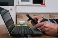 Closeup shot of a male hand using a laptop and a cellular phone with a cup of coffee Royalty Free Stock Photo