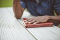 Closeup shot of a male with his hand on the bible on a wooden table with a blurred background Royalty Free Stock Photo