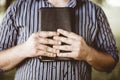 Closeup shot of a male holding the bible against his chest with a blurred background Royalty Free Stock Photo