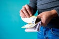 Closeup shot of a male holding a bunch of large Euro bills on a blue background