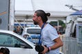 Closeup shot of a male photographer with hair in a bun against the background of cars