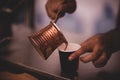 Closeup shot of a male pouring out Turkish coffee into a cup Royalty Free Stock Photo