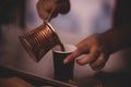 Closeup shot of a male pouring out Turkish coffee into a cup Royalty Free Stock Photo