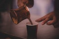 Closeup shot of a male pouring out Turkish coffee into a cup Royalty Free Stock Photo