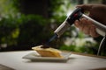 Closeup shot of a male\'s hand holding a blowtorch into a slice of pie on a plate Royalty Free Stock Photo