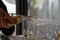 Closeup shot of a male's hand pouring alcohol in champagne glasses on tray