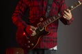 Closeup shot of a man in a check shirt playing an electric guitar in a neon light