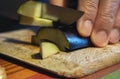 Closeup shot of a man cutting an aubergine on a wooden board