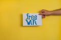 A closeup shot of a man holding a paper with the word FREE WIFI on a yellow background Royalty Free Stock Photo