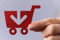 Closeup shot of a man holding a red shopping cart icon with an arrow on a grey background Royalty Free Stock Photo