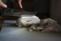 Closeup shot of a man\'s hand cutting a cooked chicken breast with a knife and fork on a board